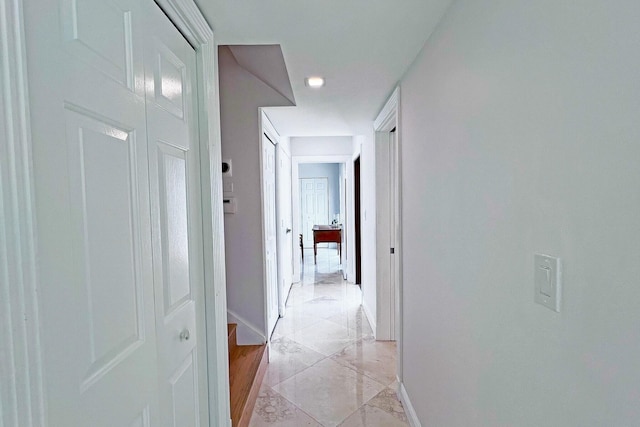 hall featuring marble finish floor and baseboards