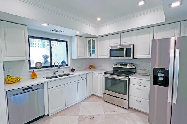 kitchen featuring a sink, white cabinets, light countertops, appliances with stainless steel finishes, and glass insert cabinets