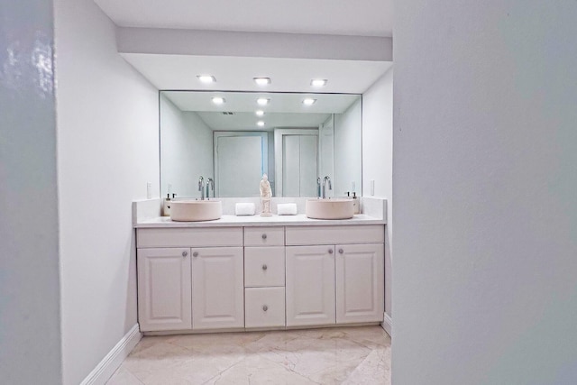 bathroom with double vanity, baseboards, and a sink