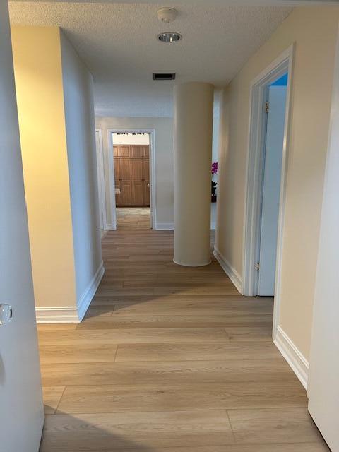 corridor featuring a textured ceiling and light wood-type flooring