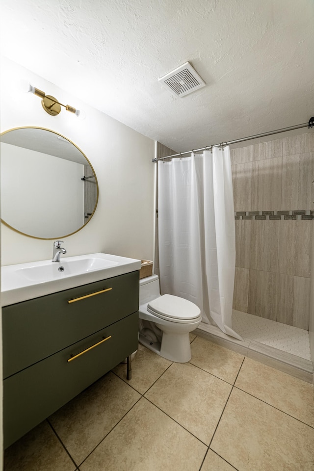 bathroom with tile patterned flooring, toilet, a textured ceiling, and vanity