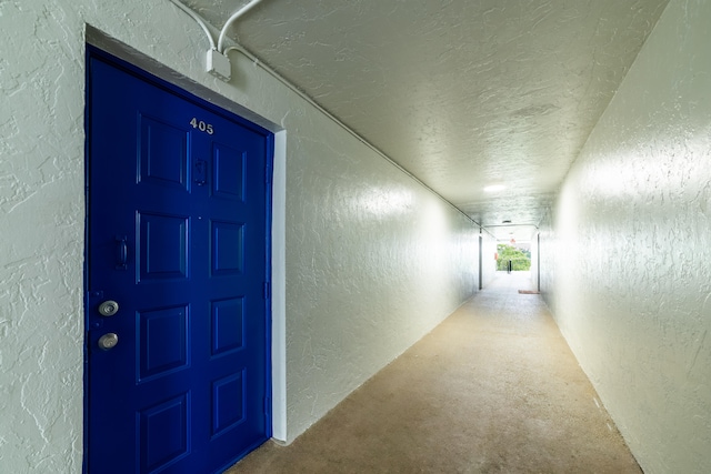 corridor with carpet flooring, a textured ceiling, and elevator