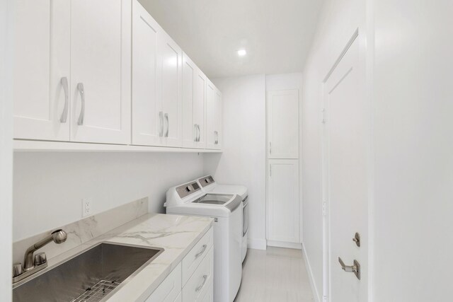 washroom with cabinets, separate washer and dryer, and sink