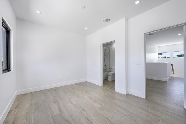 unfurnished bedroom with ensuite bathroom and light hardwood / wood-style floors