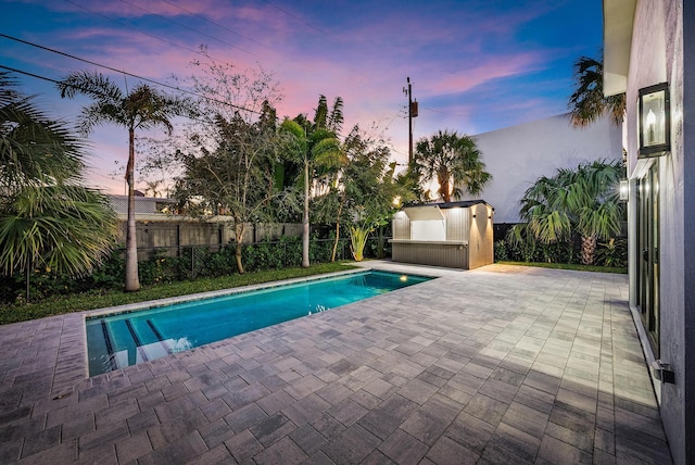 pool at dusk featuring a patio