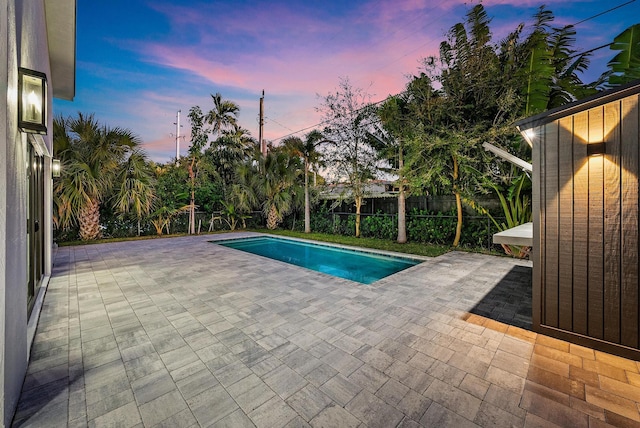 pool at dusk featuring a patio