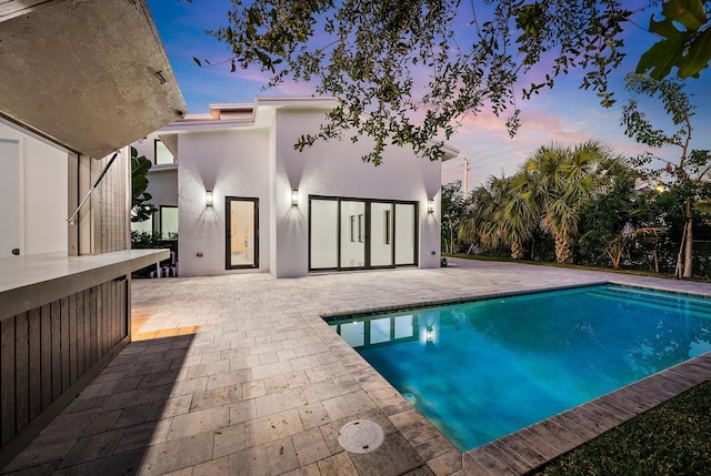 pool at dusk with a patio area