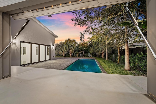 pool at dusk featuring a patio area