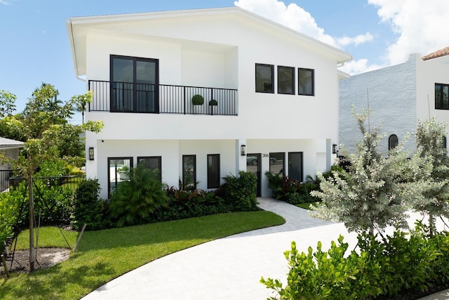 view of front facade featuring a balcony and a front yard