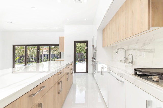 kitchen with light stone countertops, sink, and light brown cabinetry