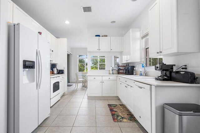 kitchen with white cabinetry, sink, light tile patterned floors, and white appliances