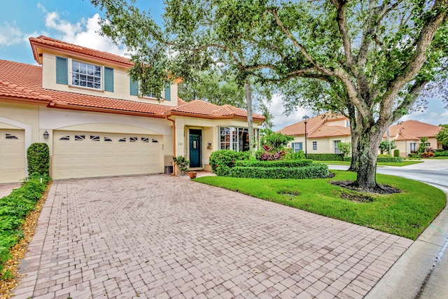 mediterranean / spanish-style home featuring a front yard and a garage