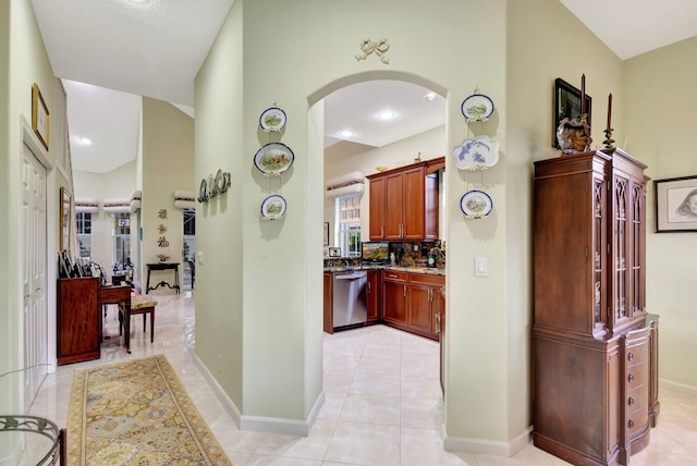 kitchen with stainless steel dishwasher, backsplash, stone countertops, and light tile patterned floors