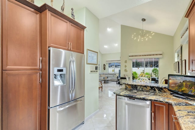 kitchen featuring light tile patterned flooring, appliances with stainless steel finishes, dark stone countertops, and decorative light fixtures