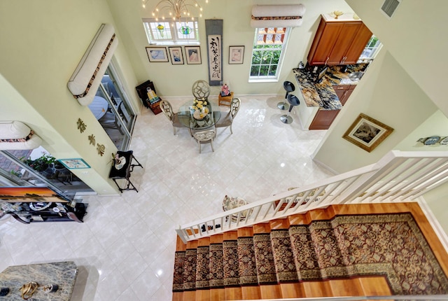 living room featuring tile walls, a notable chandelier, tile patterned floors, and a high ceiling