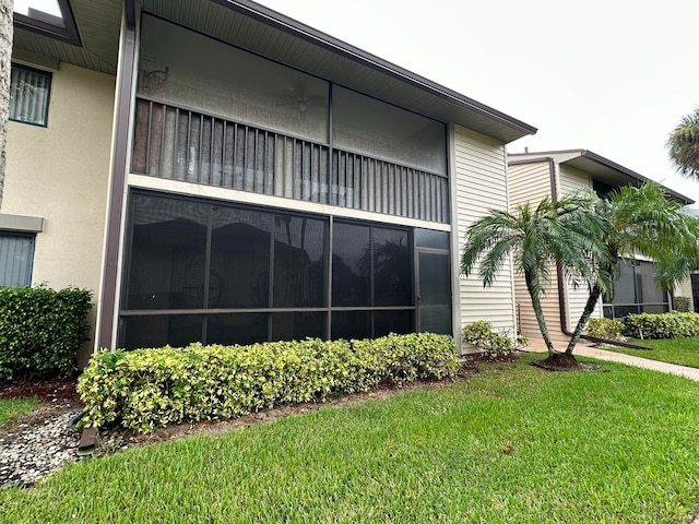 view of property exterior with a sunroom and a lawn