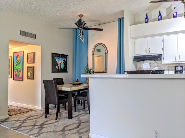 dining area featuring a textured ceiling, light tile patterned flooring, and ceiling fan