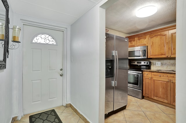 kitchen featuring light tile patterned flooring, stainless steel appliances, stone countertops, and decorative backsplash