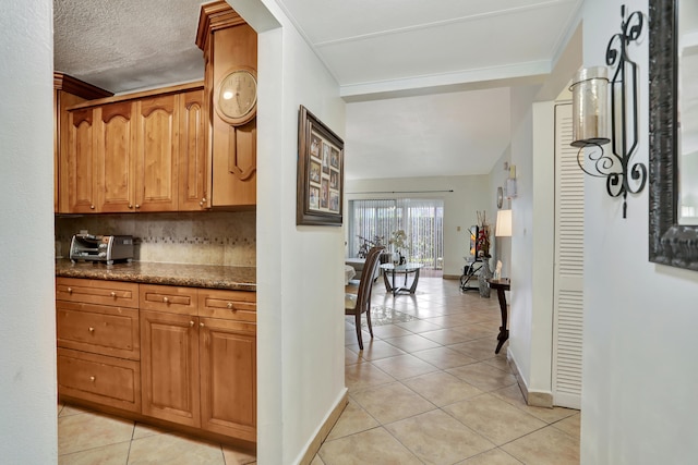 kitchen with tasteful backsplash, dark stone counters, and light tile patterned floors