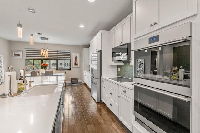 kitchen with white cabinetry, appliances with stainless steel finishes, sink, decorative light fixtures, and dark hardwood / wood-style flooring