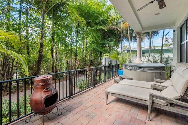 view of patio featuring ceiling fan, a hot tub, and a water view