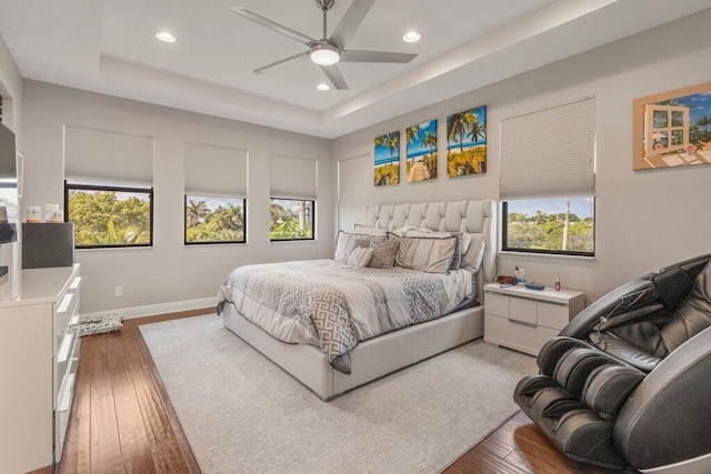 bedroom featuring ceiling fan, multiple windows, and hardwood / wood-style flooring