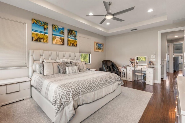 bedroom featuring a tray ceiling, dark hardwood / wood-style flooring, and ceiling fan