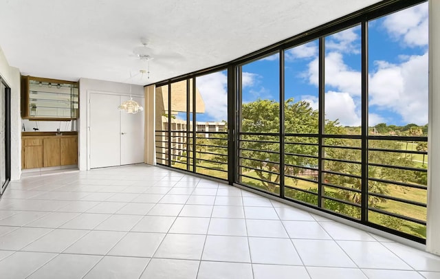 unfurnished sunroom featuring ceiling fan with notable chandelier