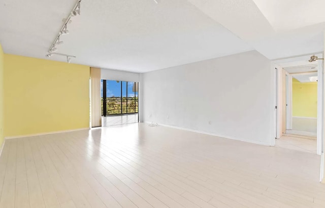 unfurnished room featuring rail lighting and light hardwood / wood-style flooring