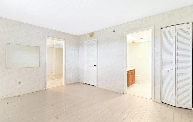 unfurnished bedroom featuring connected bathroom and light hardwood / wood-style floors