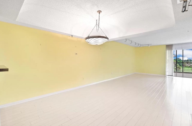 unfurnished room featuring hardwood / wood-style floors, rail lighting, and a textured ceiling