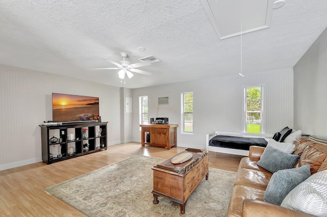 living room with ceiling fan, a textured ceiling, and light hardwood / wood-style flooring