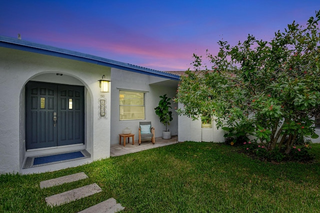 exterior entry at dusk featuring a lawn