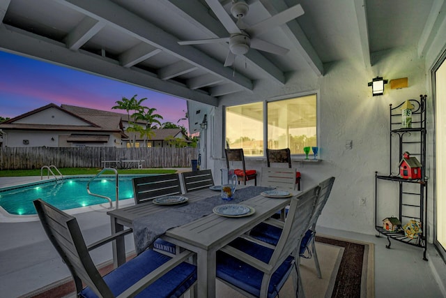 pool at dusk with ceiling fan and a patio area