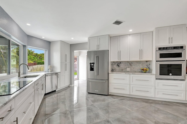 kitchen featuring sink, decorative backsplash, stainless steel appliances, and white cabinets