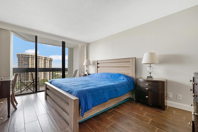 bedroom featuring baseboards, wood tiled floor, floor to ceiling windows, a textured ceiling, and access to outside