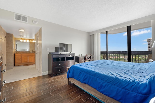 bedroom with a wall of windows, visible vents, a textured ceiling, and wood tiled floor