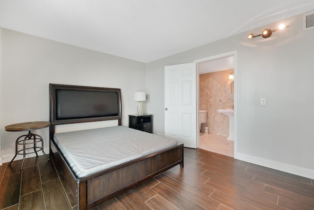 bedroom featuring ensuite bath, baseboards, visible vents, and wood tiled floor