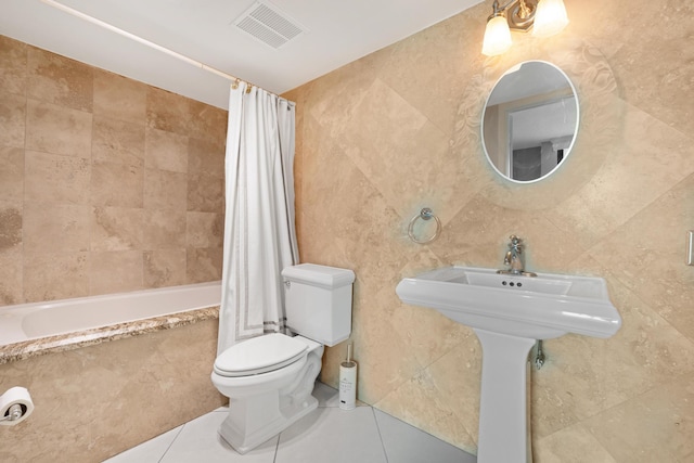 full bathroom with visible vents, tile walls, toilet, tiled shower / bath, and tile patterned floors