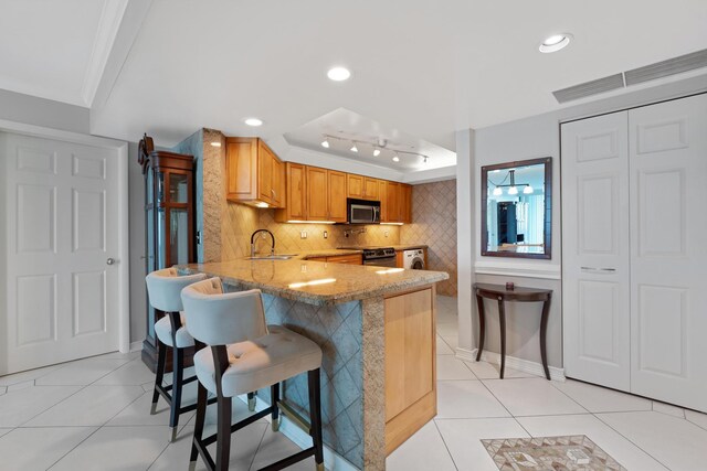 kitchen with light stone countertops, sink, light tile patterned floors, decorative backsplash, and range with electric stovetop