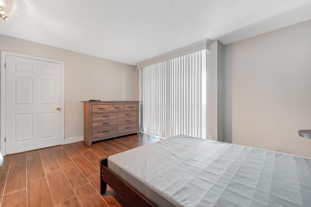 bedroom featuring wood finished floors, baseboards, and a textured ceiling