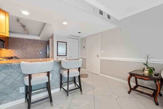 kitchen with tasteful backsplash, light tile patterned floors, crown molding, and light brown cabinets