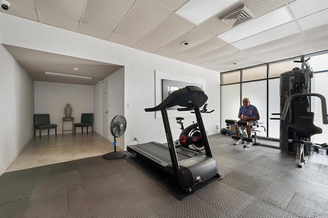 workout room featuring floor to ceiling windows, a paneled ceiling, and visible vents