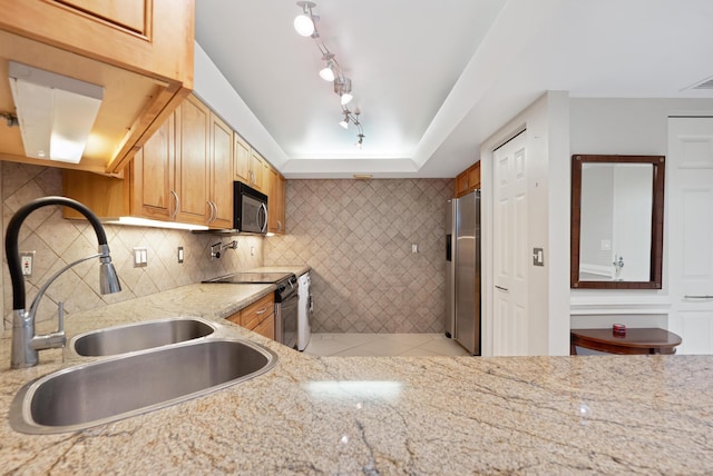 kitchen featuring black microwave, light stone countertops, stainless steel fridge with ice dispenser, electric range, and a sink