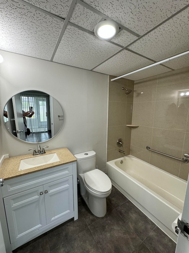 full bathroom featuring toilet, a drop ceiling, tile patterned flooring, tiled shower / bath combo, and vanity