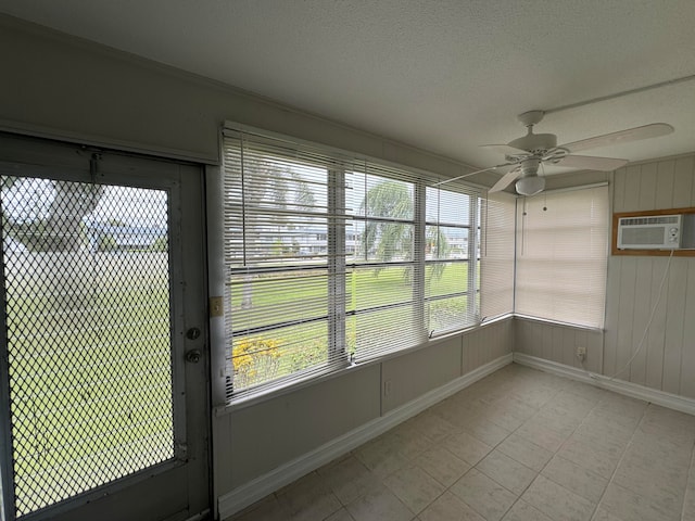 unfurnished sunroom with ceiling fan, a wall unit AC, and plenty of natural light