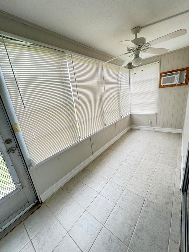 unfurnished sunroom featuring a wall mounted AC and ceiling fan