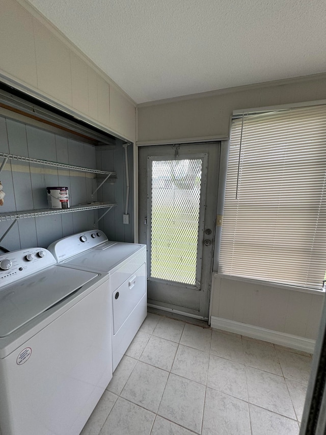 laundry area featuring independent washer and dryer, light tile patterned floors, and a textured ceiling