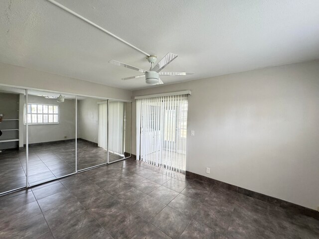 unfurnished bedroom with ceiling fan, a textured ceiling, a closet, and tile patterned flooring