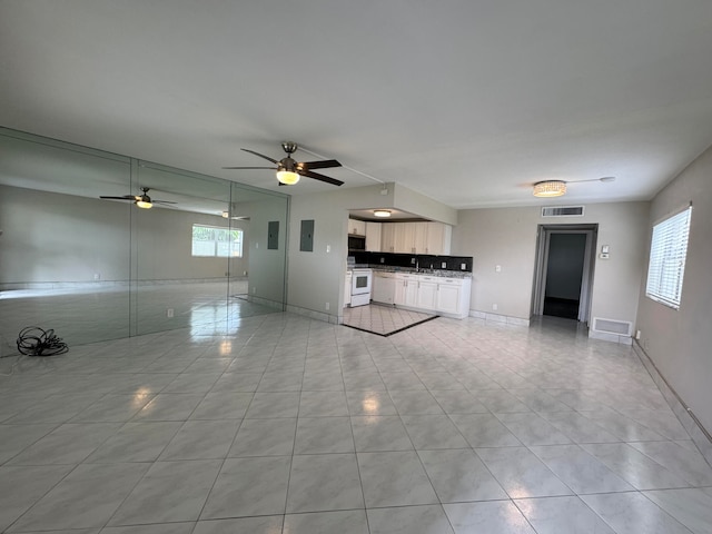 unfurnished living room with ceiling fan, sink, and light tile patterned floors